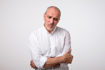portrait of mature handsome man in white shirt with serious and sad expression on face. Negative facial emotion