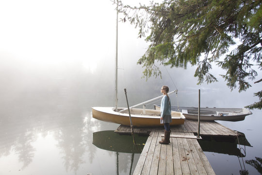 Twelve year old girl stands on a dock on a foggy morning on Fletcher Bay
