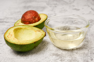 Avocado oil and fresh avocado on concrete table.