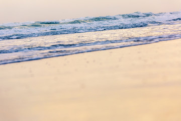 small wave coming to the beach and glassy fluffy white breaking wave on the sand with gold sunlight for background