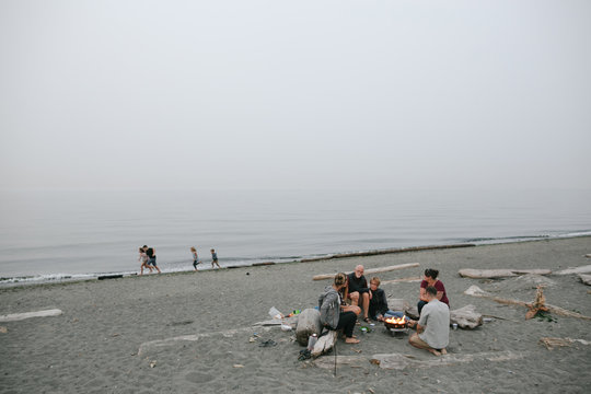 Multi generational family hanging out together around fire on the beach