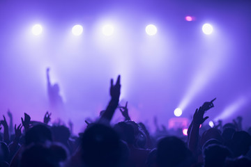 Sillhouettes of concert crowd in front of bright stage lights