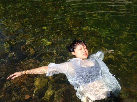 Bare upper body of the woman, lying down into the water