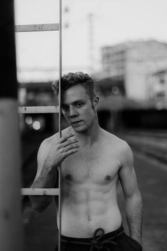 barechest young man on a railway