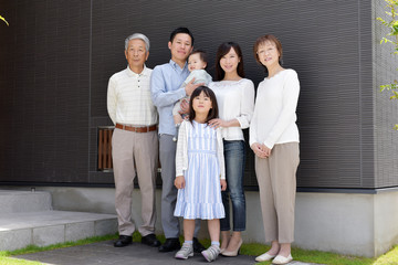 家の前に立つ笑顔の3世代家族