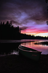 Canoe on lake in forest at sunset