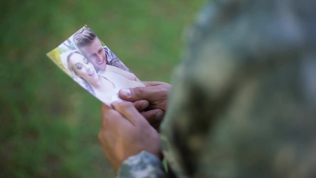 Soldier holding happy couple photo, missing girlfriend, memories, separation