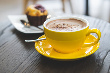 hot chocolate in yellow mug on the wooden table.