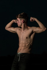 Naklejka premium Young adult male posing shirtless at sunset