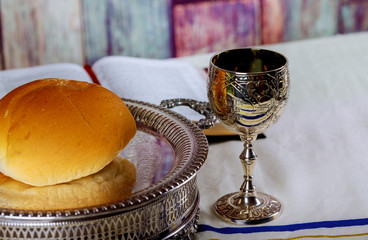 Taking Communion. Cup of glass with red wine, bread and Holy Bible on wooden table close-up.