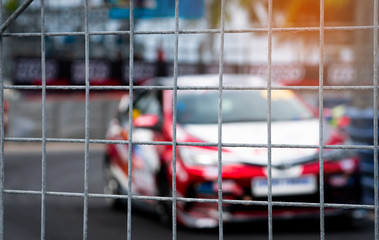 Motorsport car racing on asphalt road. View from the fence mesh netting on blurred car on racetrack...