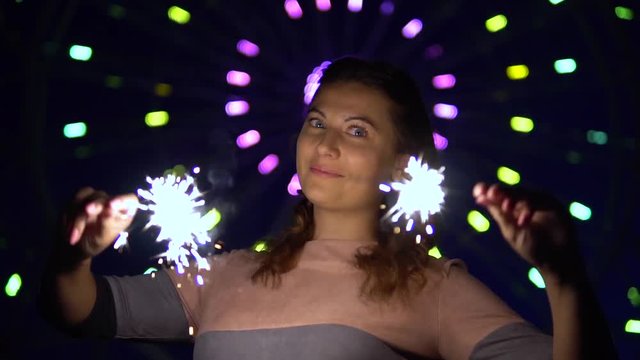 A beautiful girl is happy with a holiday with fireworks in her hands. slow motion. HD