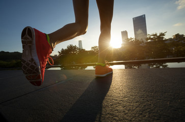 Healthy lifestyle woman runner legs running on sunrise city
