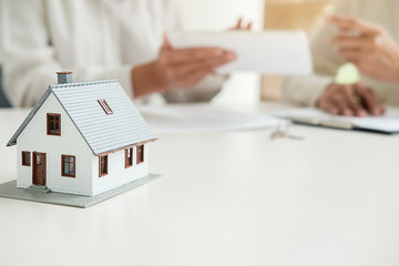 House model with real estate agent and customer discussing for contract to buy house, insurance or...