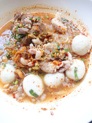Closeup Spicy TOM YAM Pork Noodles Soup with Pork Balls, chilly pasted and lime juice / Noodles in Thai spicy tom yum soup with pork