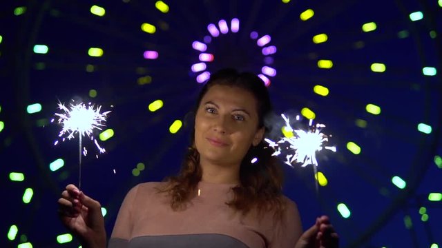 An attractive girl is happy with a holiday with fireworks in her hands. slow motion. HD