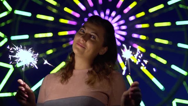 An attractive girl enjoys the holiday with fireworks in her hands having a good mood. slow motion. HD