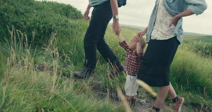 Little toddler walking on moor with mother and grandfather