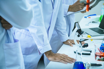 Fototapeta premium The research team is analyzing the results of biochemical experiments by using microscope, chemical in beaker and save the data in the laptop at laboratory room.