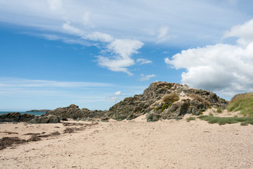 Fototapeta na wymiar Volcanic rock, blue sky and clouds on Newborough beach, Anglesey, Gwynedd, Wales, United Kingdom