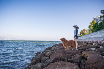 Golden retriever and Girl on the rocks by the sea