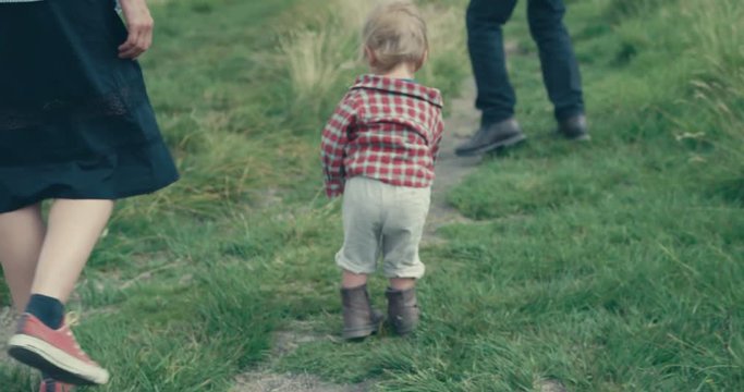 Little toddler walking with mother and grandfather on the moor