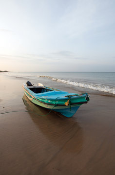 Sunset view of small fishing boat on Nilaveli beach in Trincomalee Sri Lanka Asia
