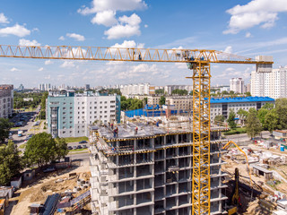 birds eye view of construction site. apartment building with scaffolding and cranes against blue sky