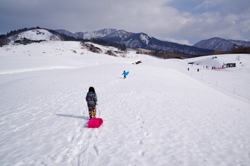 Fototapeta na wymiar 雪山でソリ遊びをする子供