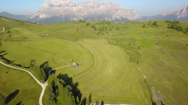 Aerial drone landscape of the meadows at high altitudes, forming gentle hills. Sella massif in the background. Dolomites, Alta Badia, Sud Tirol, Italy