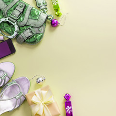 Christmas background yellow Flat Lay fashion accessories handbag sandals phone gift box bow balls.