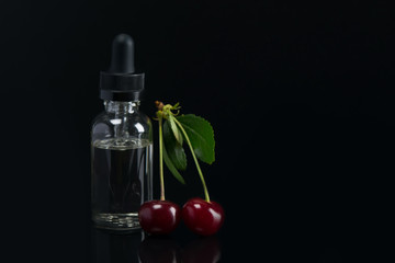 aroma oils in a can with a dispenser, next to the fruit of ripe cherries. lying on black background with reflection.
