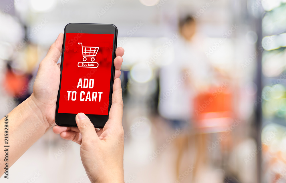 Poster Hand holding mobile add to cart product to purchase online with apps screen at blur bokeh supermarket background,online shopping concept,digital lifestyle.