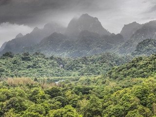 Wild monsoon clouds cover forested mountainous slopes in Kanchanaburi Province, eastern Thailand