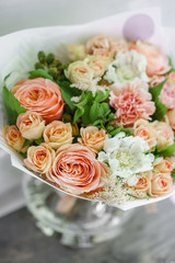 Work florist. Beautiful spring bouquet. Arrangement with mix flowers. The concept of a flower shop, a small family business. Color light peach and orange
