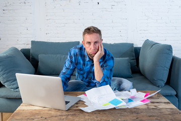 Worried and stressed man calculating bills, tax expenses and counting home finances sitting on the...