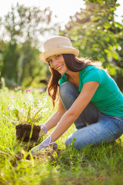 Young happy woman is planting a flower in her garden. 