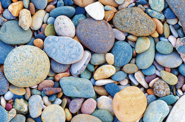 Bright background of multi-colored round stones, sea pebbles close up.