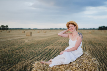 Naklejka na ściany i meble Happy stylish cheerful caucasian woman walking and spending time in summer wheat field. Beautiful woman portrait outdoors. Love, beauty, happiness concept.
