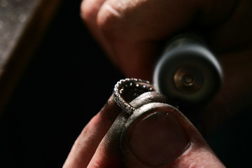 Close up of the hands of a goldsmith while he is making a diamond ring. Concept: jewelry, gold,...