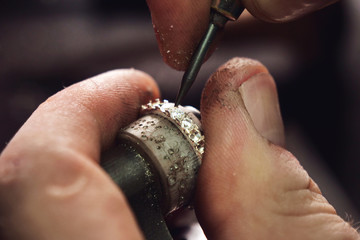 Close up of the hands of a goldsmith while he is making a diamond ring. Concept: jewelry, gold, fashion - obrazy, fototapety, plakaty