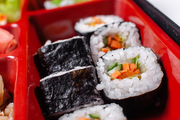 Fresh food portion in japanese bento box with salad, main course. Sushi roll with vegetables. Vegetarian dish.