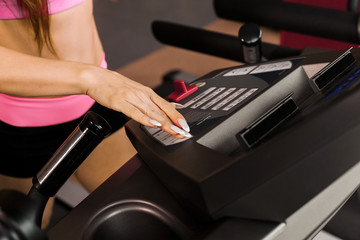 womans hand at the control panel of the treadmill in the gym. Concept of cardio exercises and healthy way of life