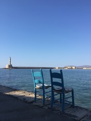 Leuchtturm mit Hafen und zwei Stühlen