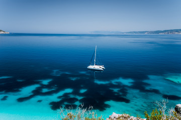 Fteri beach, Cephalonia Kefalonia, Greece. White catamaran yacht in clear blue transparent sea water surface