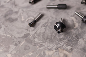 Scattered set of steel router bit for milling cutter on old broken worn gray concrete floor with...