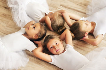 Top view of four dancers lying on the parquet floor of a dance school, who rest after exercising. Concept of: team, teaching, ambition, relaxation.
