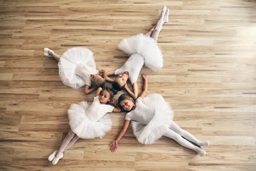 Crédence de cuisine en verre imprimé École de danse Top view of four dancers lying on the parquet floor of a dance school, who rest after exercising. Concept of: team, teaching, ambition, relaxation.