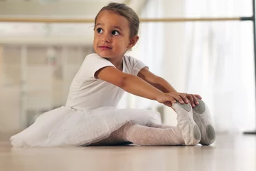 Cercles muraux École de danse Portrait of a beautiful very young girl, in a dance school wearing a white tutu, she trains alone to learn new dance steps. Concept of: ambition, education, elegance and love for the dance...
