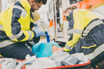 Paramedics performing first aid at ambulance, helping a woman